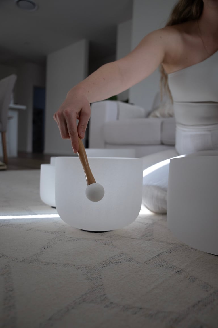Hand holding a wooden spoon over a white ceramic bowl in a minimalist kitchen setting